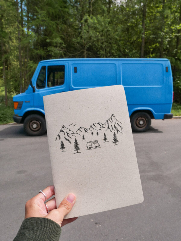 Notizheft aus Graspapier mit schlichter Zeichnung von einem Campervan in einer Berglandschaft